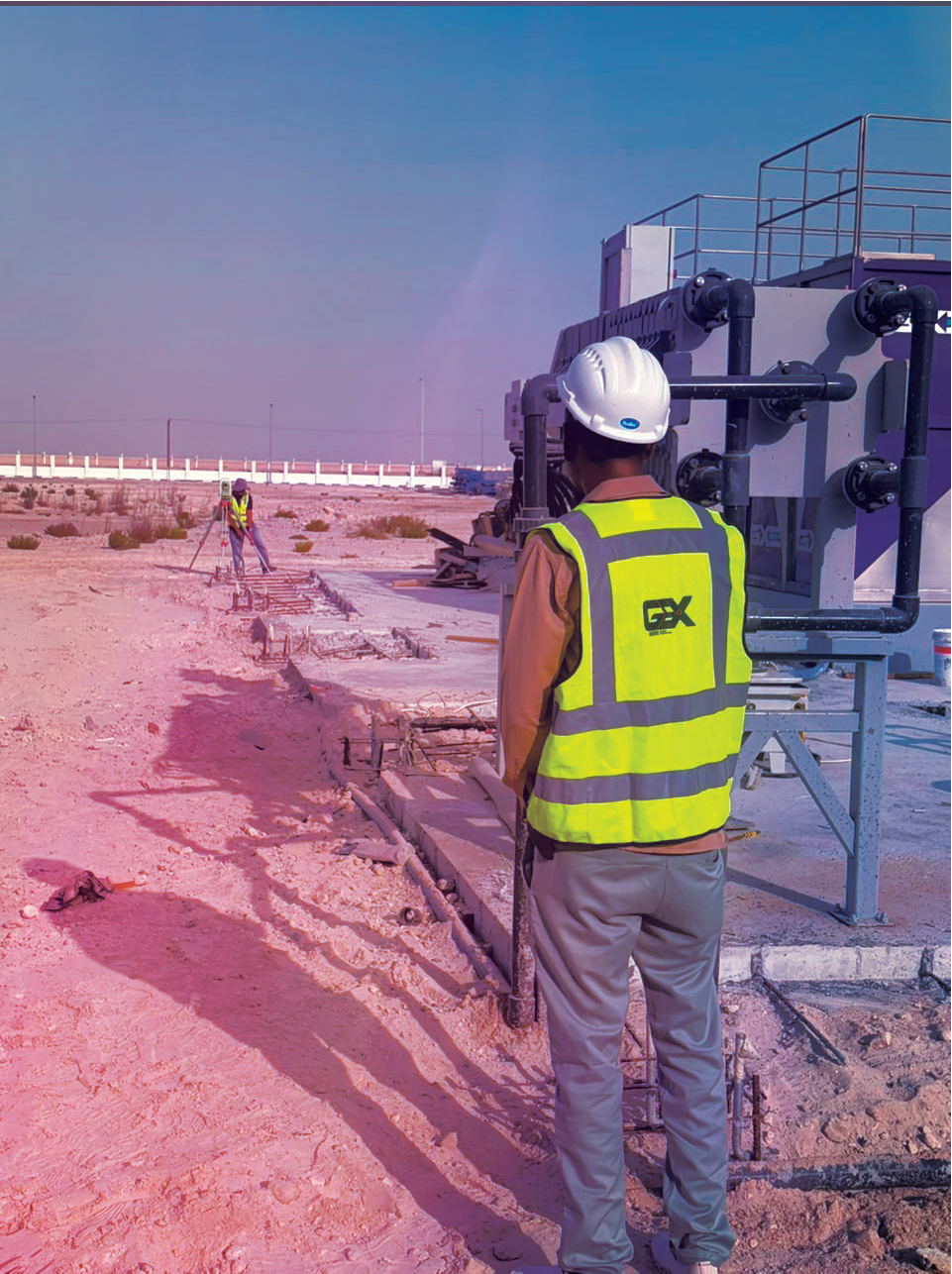 GeoX field team taking measurements alongside industrial pipework.